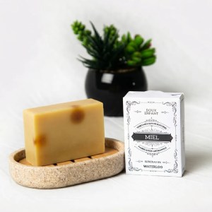 Savon au miel artisanal avec reflets ambrés et packaging élégant.